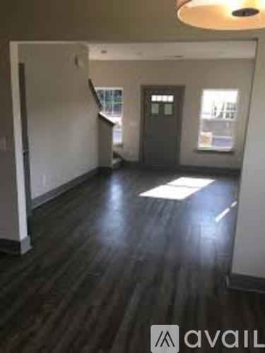 A hallway with a wooden floor and a door on the right side.