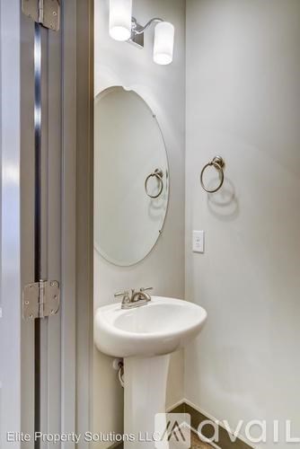 A white sink in a bathroom with a round mirror above it.