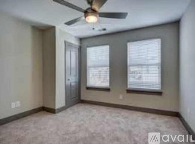 A room with a ceiling fan and two windows.