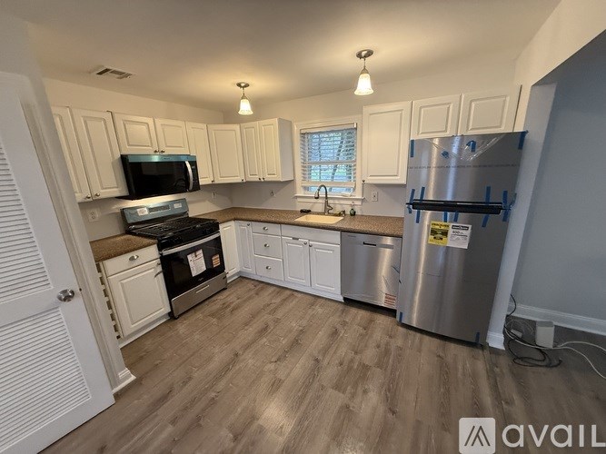 A white house with a black roof and a white fence.