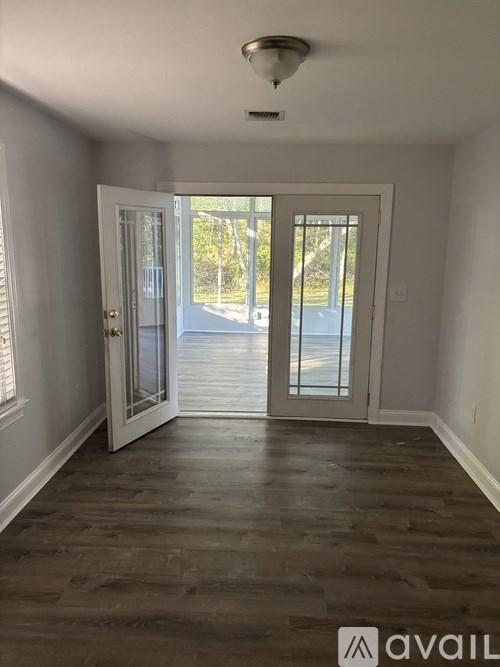 A room with a wooden floor and a glass door leading outside.