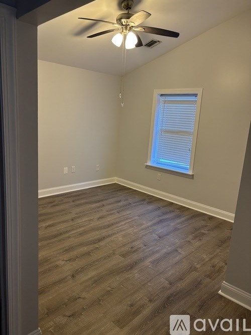A room with a ceiling fan and wooden flooring.