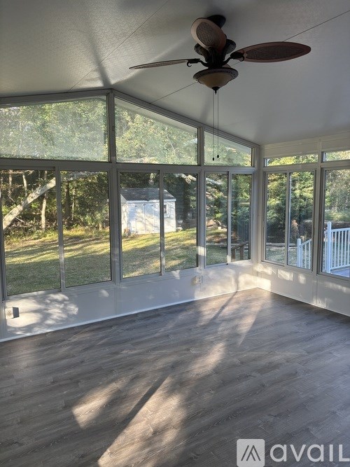 A sunny day in a room with a ceiling fan and large windows.
