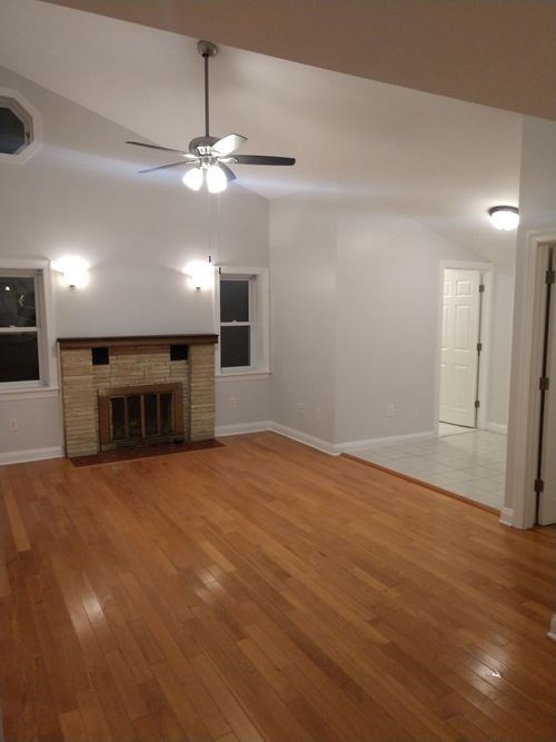 A room with a fireplace and wood flooring.