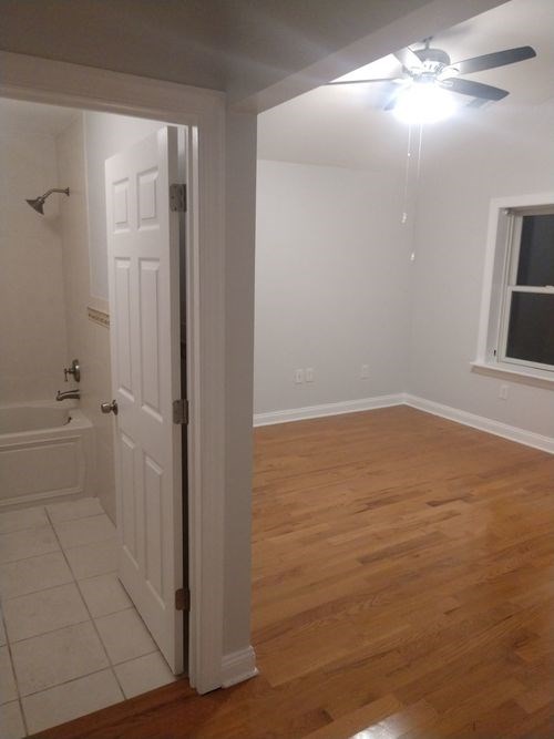 A room with a ceiling fan and a door.