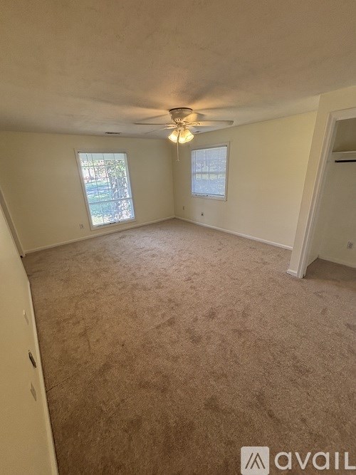 A room with carpeted floor and two windows.