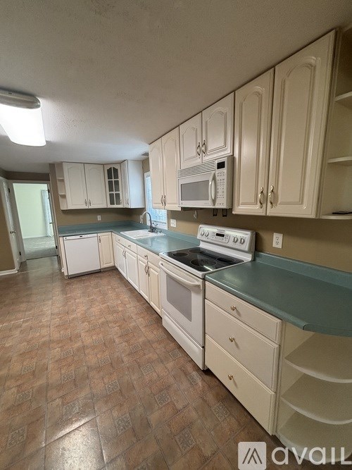 A kitchen with white cabinets and a tiled floor.