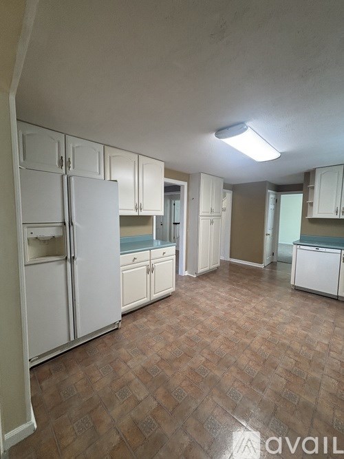 A kitchen with white cabinets and a brown floor.