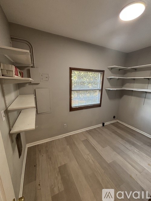 A room with a window and shelves on the wall.
