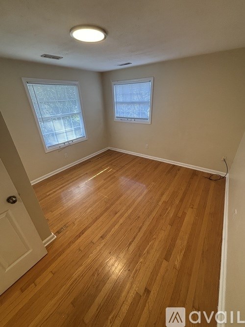 A room with wooden floors and two windows.