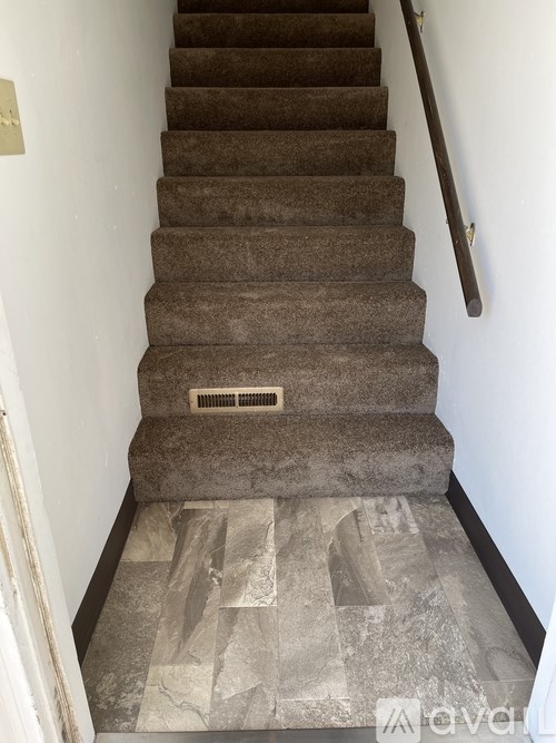 A staircase with a carpeted runner and a metal handrail.