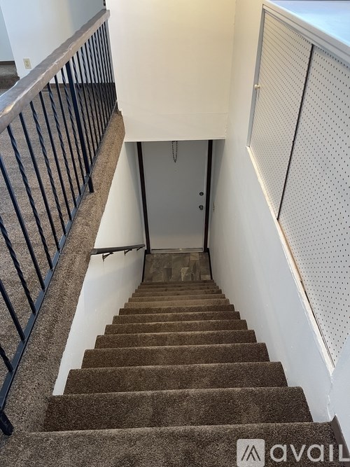 A staircase with a carpeted runner and a metal railing.