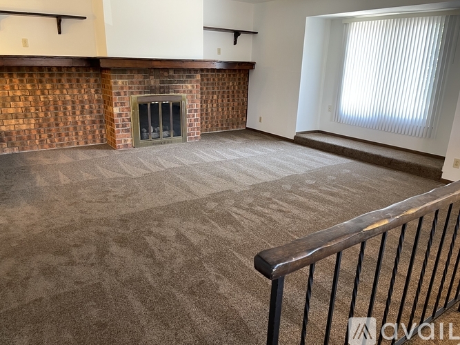 A living room with a fireplace and carpeted floor.
