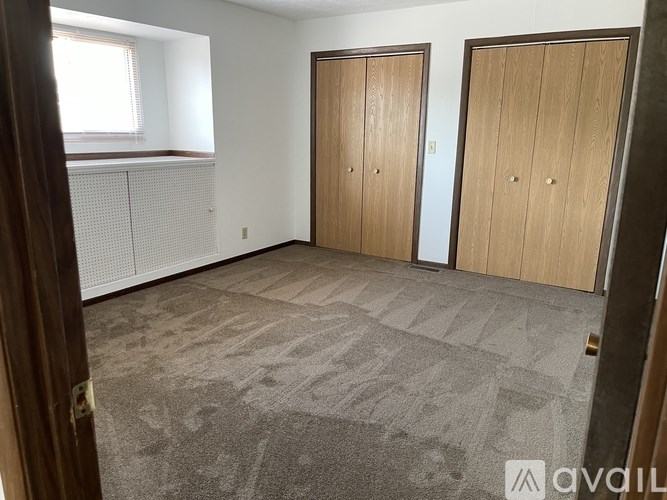 A room with two wooden doors and a carpeted floor.