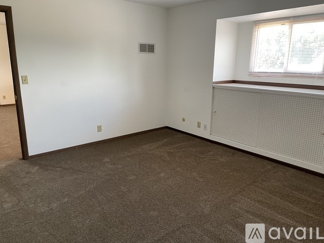 A room with a carpeted floor and a window with blinds.