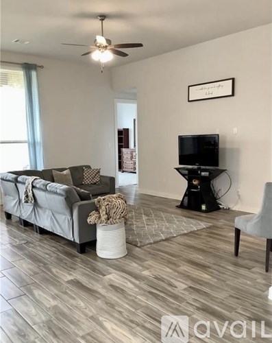 A living room with a grey couch and a television on a stand.