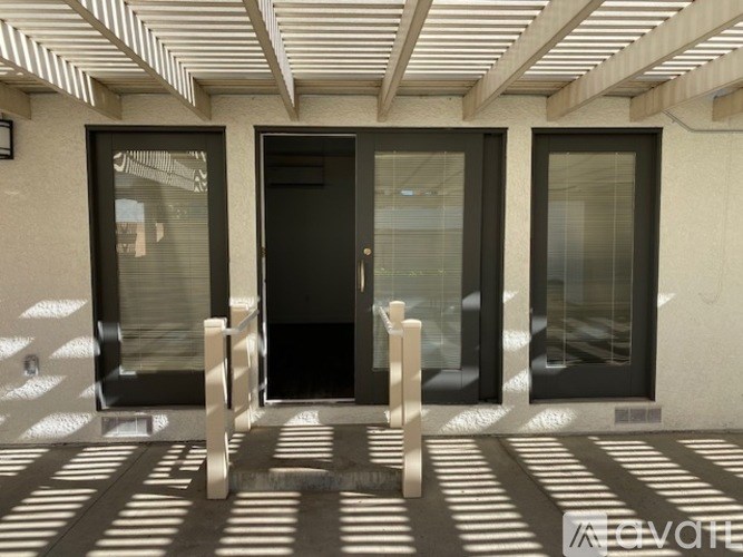 A modern house entrance with a black door and two windows.