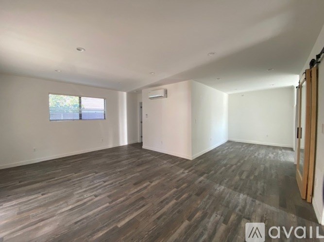 A spacious room with wooden flooring and a window.