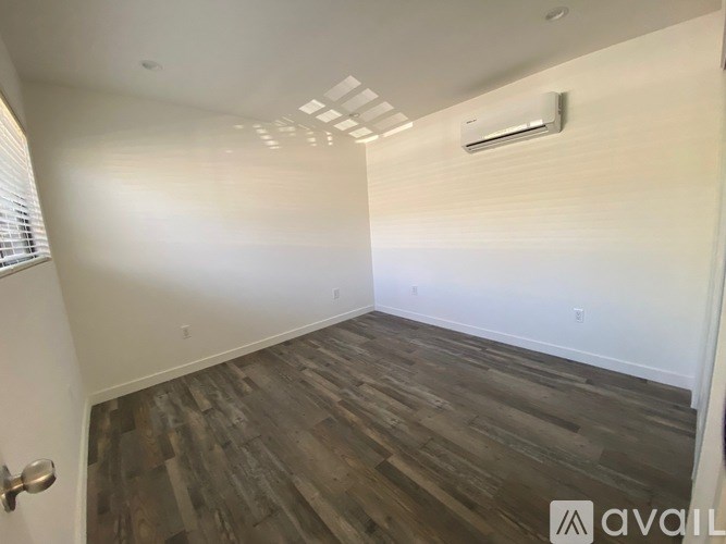 A room with wooden flooring and white walls.