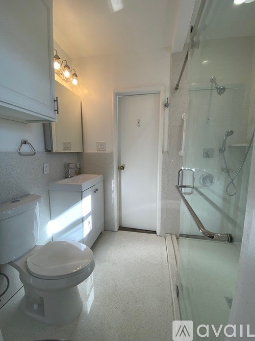 A white toilet in a small bathroom with a glass shower door.