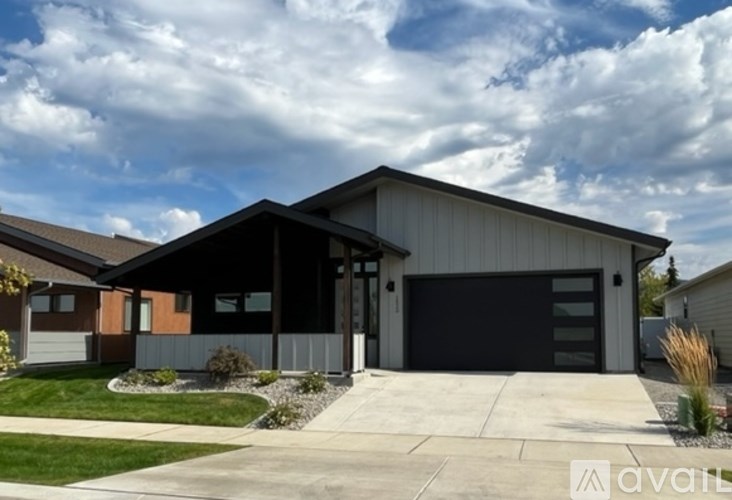 A modern house with a black garage door is for sale.