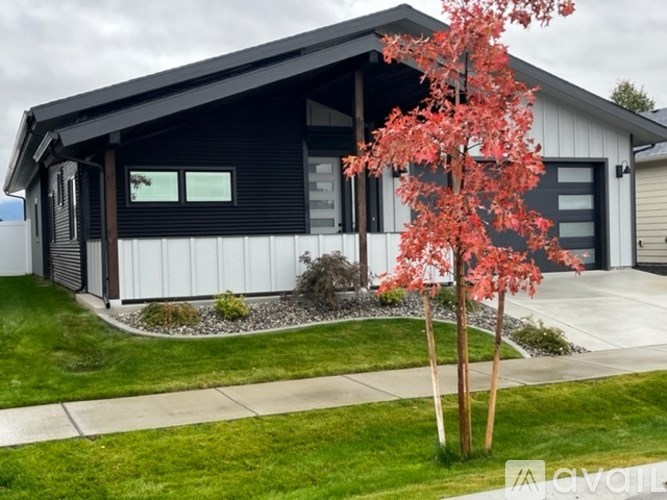A modern house with a red tree in front.