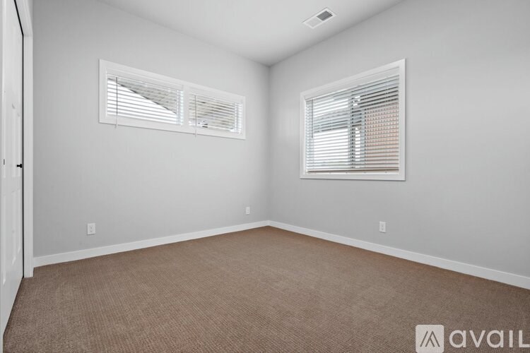 A room with two windows and carpeted flooring.