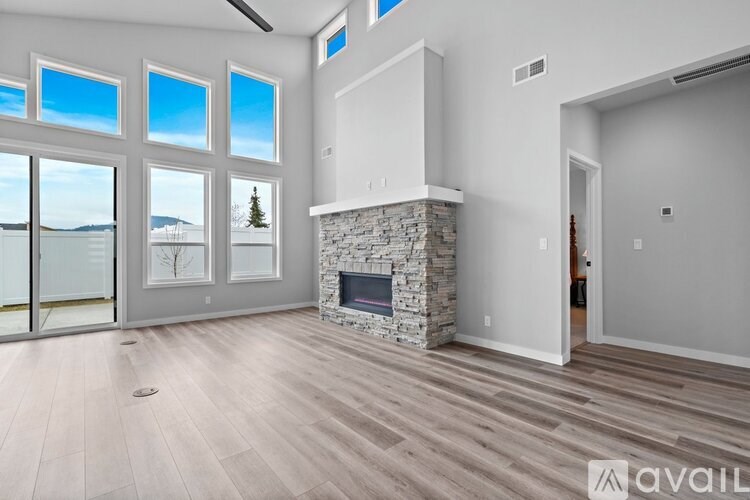 A modern living room with a stone fireplace and a large window overlooking a snowy landscape.