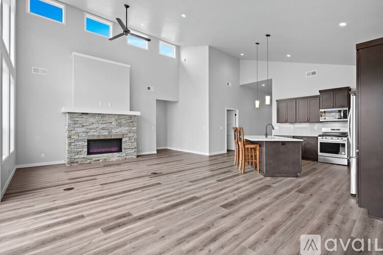 A modern kitchen with a stone fireplace and wooden flooring.