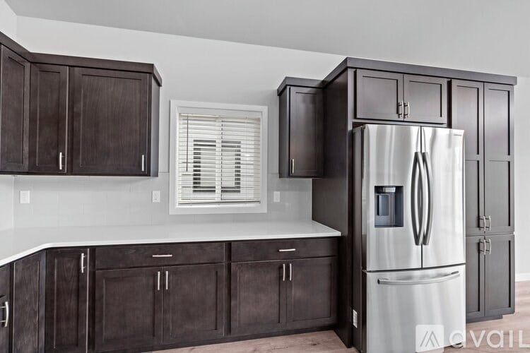 A kitchen with dark brown cabinets and a white fridge.