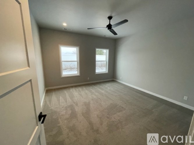 A room with a ceiling fan and two windows.