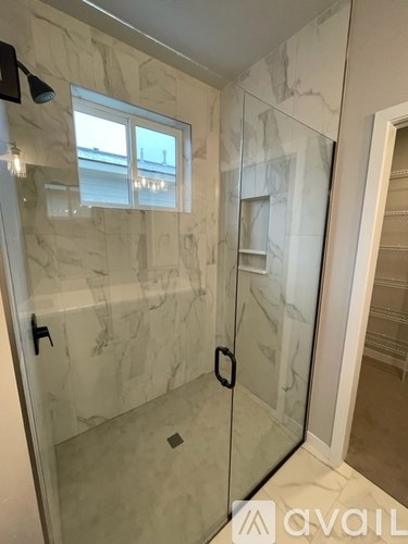 A bathroom with a marble wall and a glass shower door.