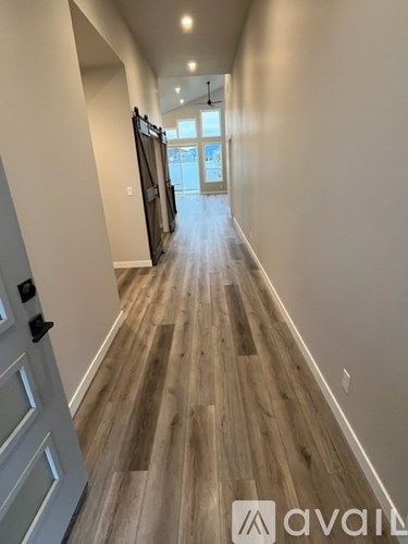 A long hallway with wood flooring and white walls.