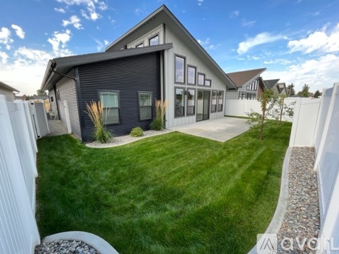A modern house with a grey exterior and a white picket fence.
