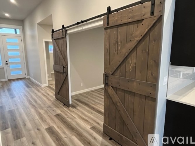 A room with a sliding barn door and wood flooring.