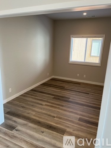 A room with wooden flooring and a window with blinds.