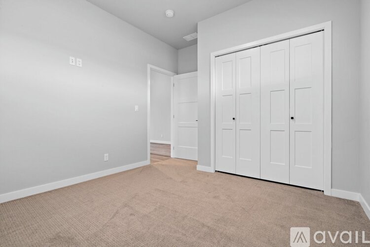 A room with white walls and a carpeted floor with a white door on the right.