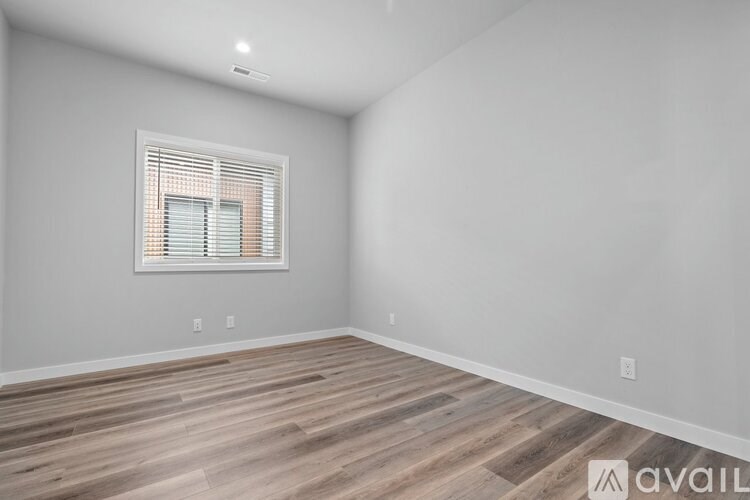A room with wooden flooring and a window with blinds.