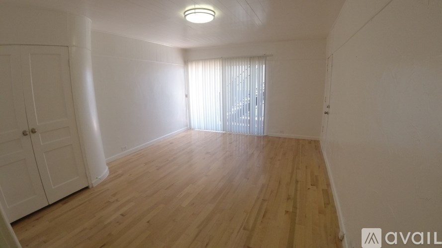 A room with wooden flooring and a window with blinds.