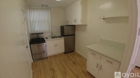 A kitchen with white cabinets and a wooden floor.
