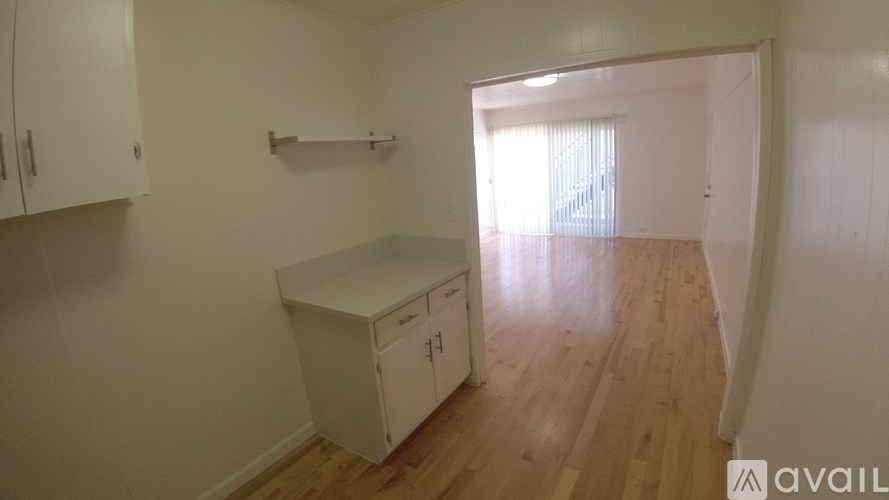 A kitchen with white cabinets and a wooden floor.