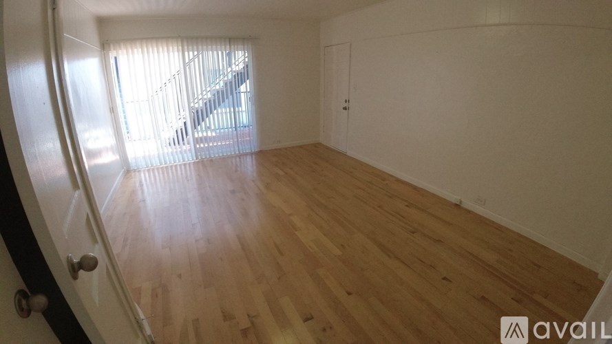 A room with wooden flooring and a window with blinds.