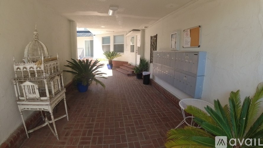 A balcony with a chair, potted plants, and a birdcage.