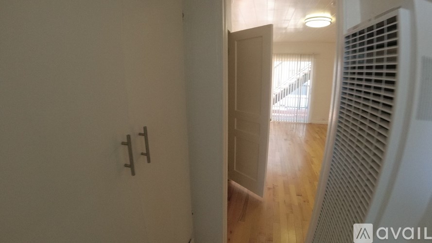 A room with a white wall and a door leading to another room.