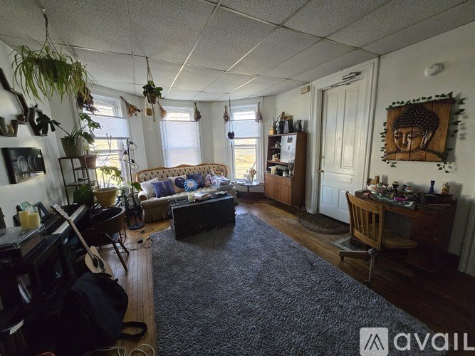 A living room with a couch, a guitar, and a backpack on the floor.