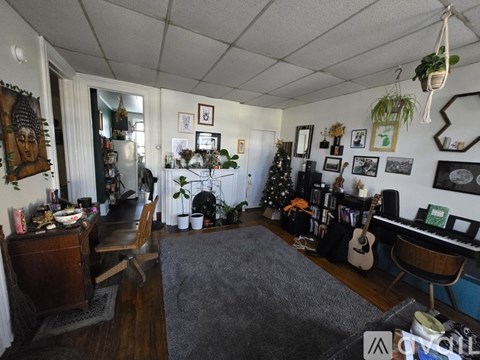 A room with a grey carpet and a piano.
