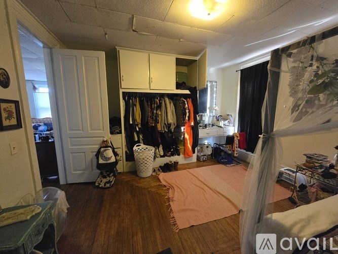 A room with a white door and a white cabinet with clothes hanging on it.