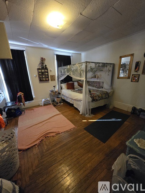 A bedroom with a bed and a canopy, a dresser, and a window with curtains.