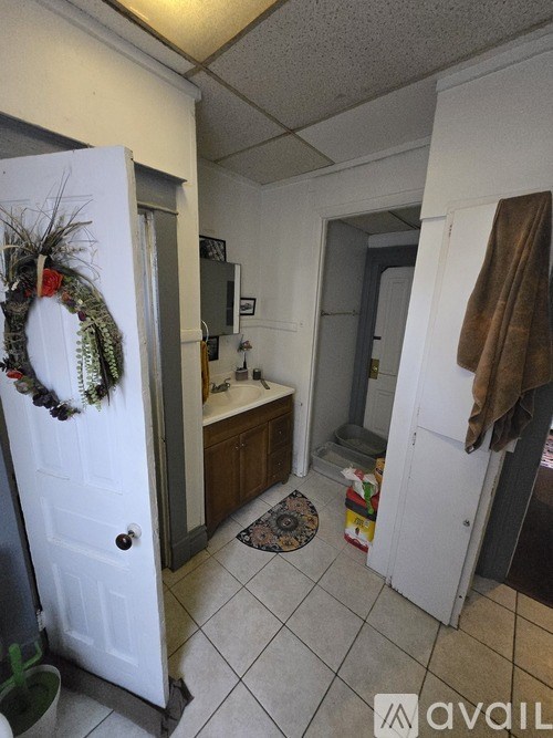 A white door with a wreath on it is in a room with a white door and a brown coat hanging on the wall.