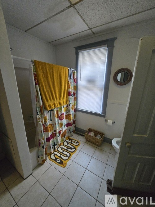 A bathroom with a yellow shower curtain and a yellow rug on the floor.
